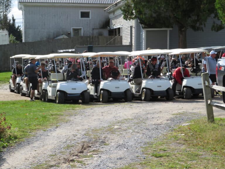 Golf carts parked in a row with passengers.
