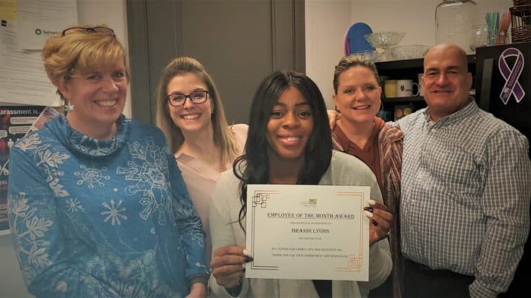 Employee receives monthly award with colleagues.