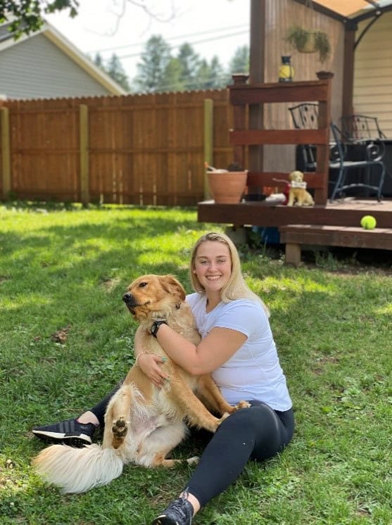 Woman hugging a golden dog in the backyard.
