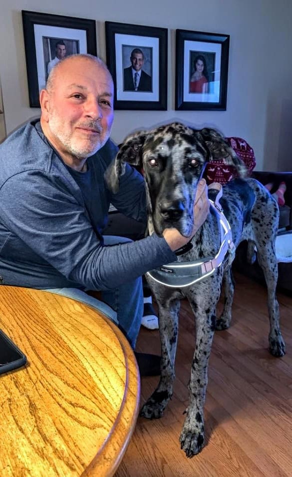 Man with Great Dane dog indoors.