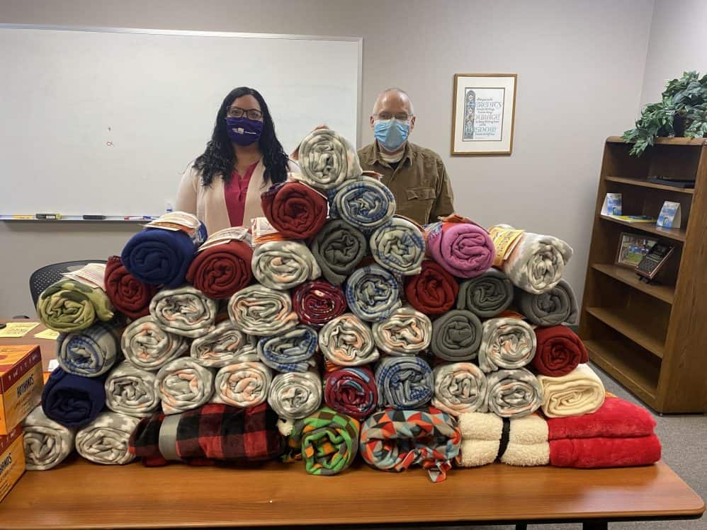Two people behind stacked blankets display.