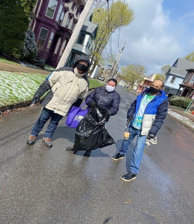 People collecting trash on a neighborhood street.
