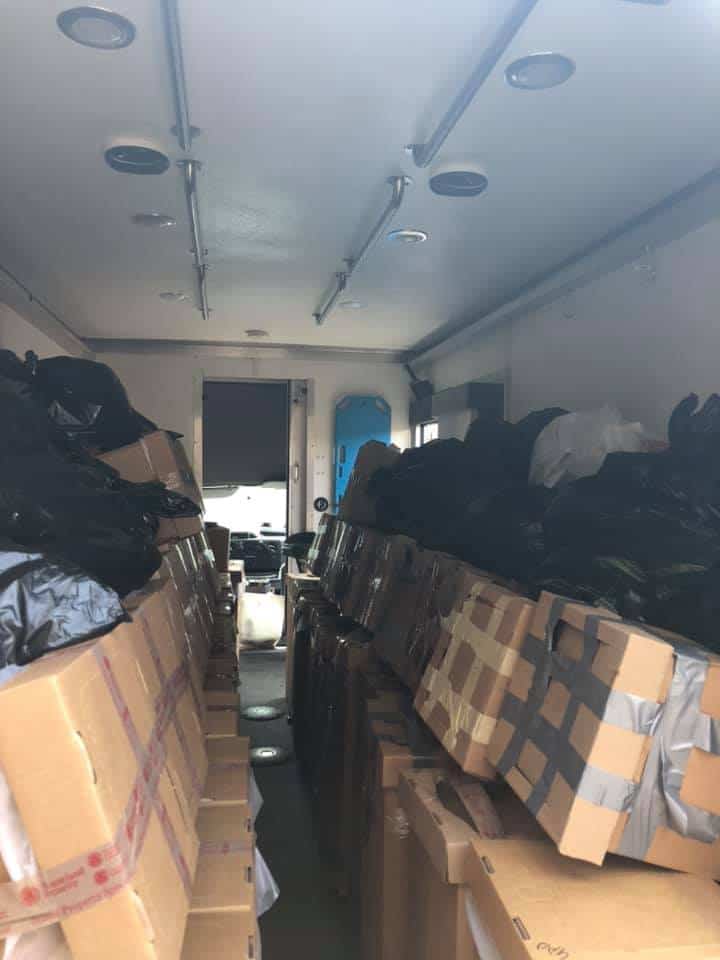 Packed storage room with boxes and black bags.