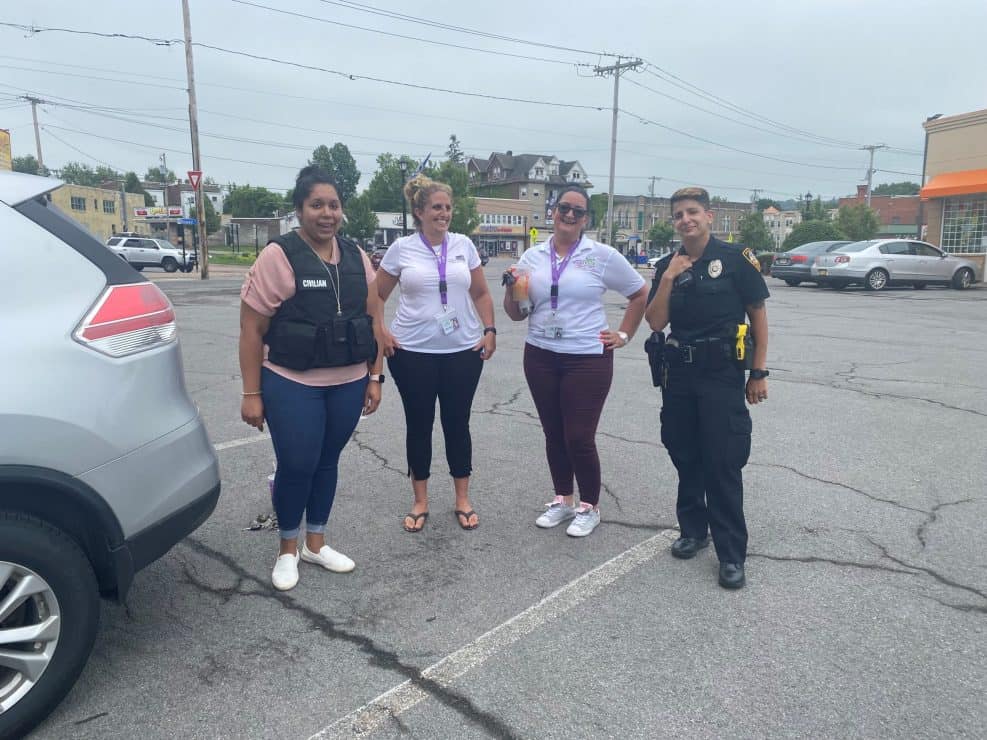 Four people pose together in a parking lot.
