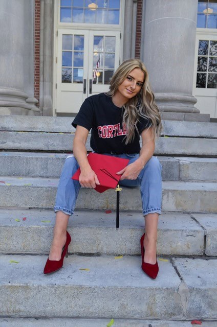 Woman sitting on steps with red accessories.