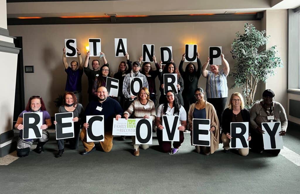 Group holding signs: Stand Up For Recovery