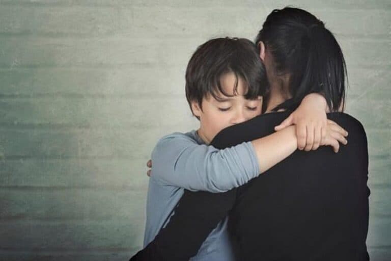 Child hugging adult with eyes closed, emotional moment.