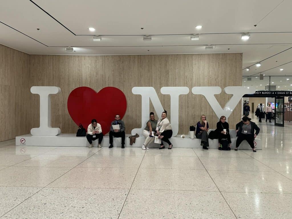People sitting on I Love NY sign indoors