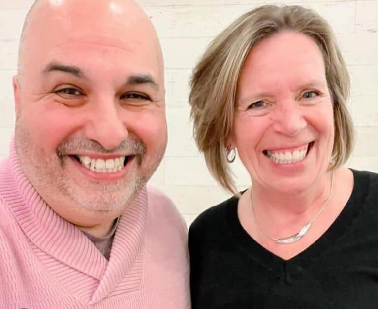 Two people smiling together indoors.