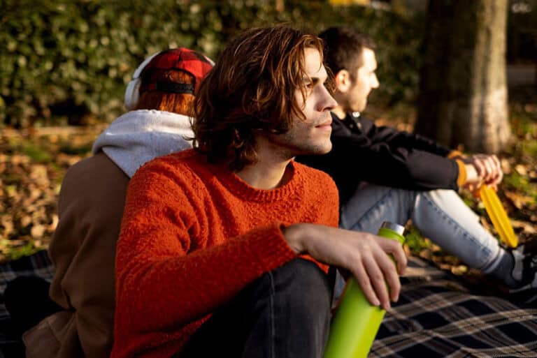 Three people sitting outdoors in a sunny park.