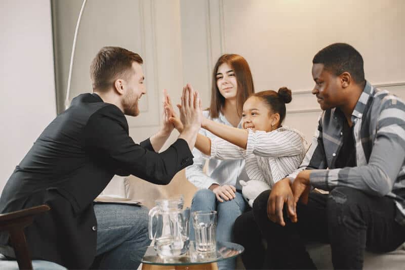 Group of friends high-fiving in living room.