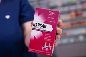 Person holding Narcan nasal spray box.