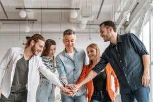 Team smiling with hands together in office.