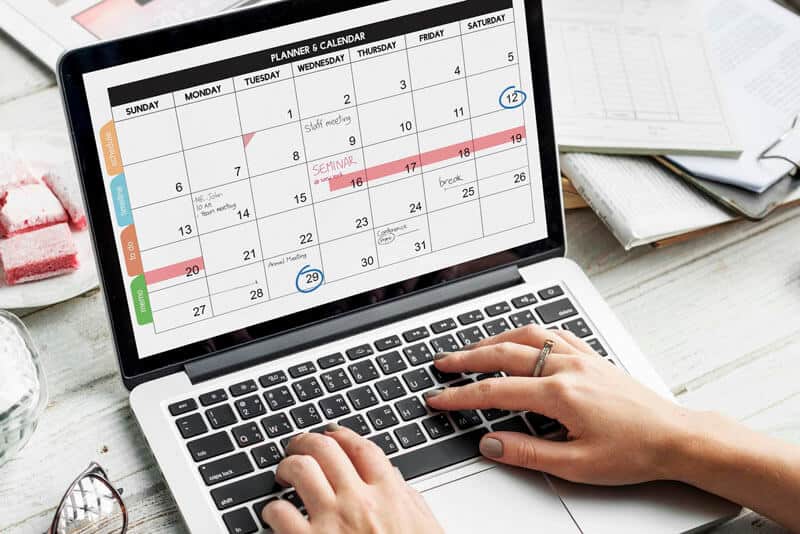 Planning calendar on laptop screen with hands typing.