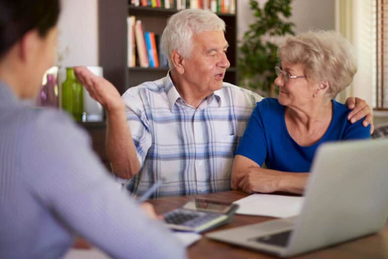 Elderly couple discussing home finances at table.
