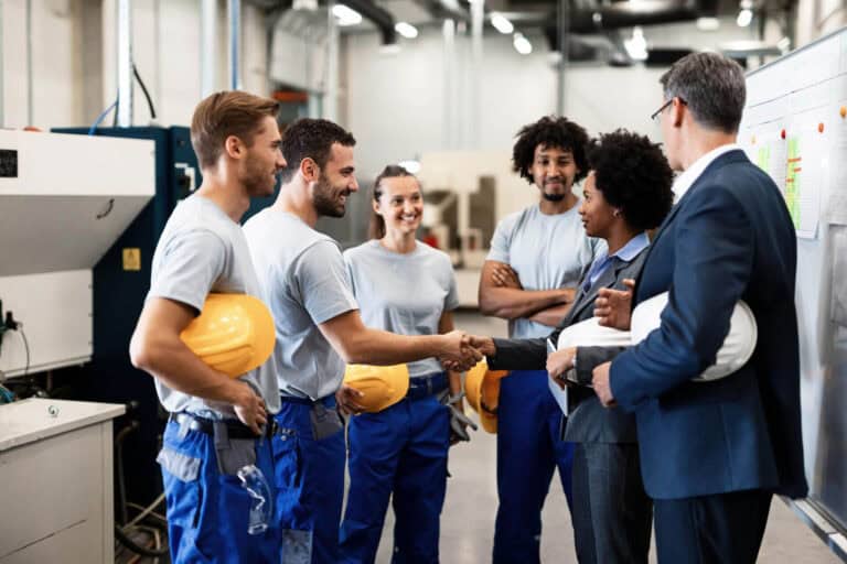 Factory workers handshake with managers in meeting.